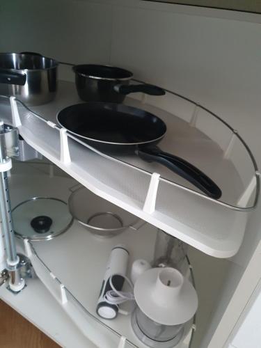 a glass shelf with pots and pans on it at Apartament Imara-klimatyzacja, miejsce parkingowe in Łódź