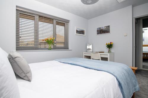 a white bedroom with a bed and a desk at B’s house in Simpson