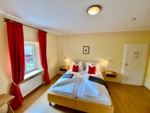 a bedroom with a large bed with red pillows at Schloss Hotel & Wellness Ering in Ering
