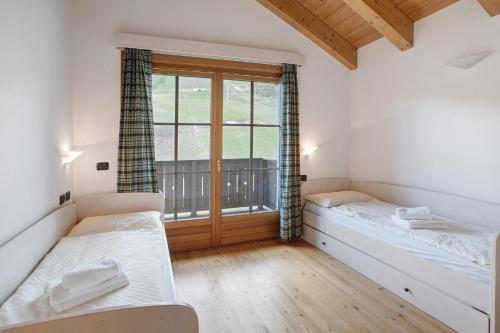 1 dormitorio con 2 camas y ventana en Baita Valandrea 3, en Livigno