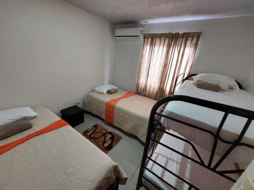 um pequeno quarto com 2 camas e uma janela em Aptos Casa Caribe, habitaciones privadas en aptos compartidos & aptos completos con auto entrada em Puerto Limón