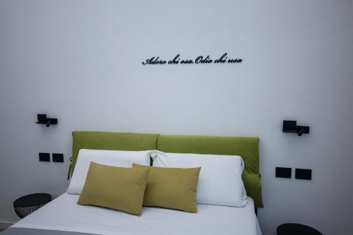 a white bed with a green headboard and two pillows at MAZZINI PALACE in Misterbianco