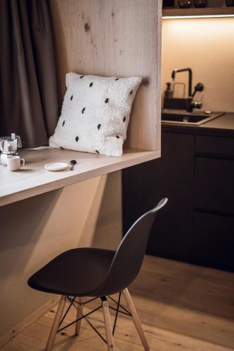 a black chair sitting next to a table with a pillow at Rousa little guesthouse Cosy in Rasun di Sopra