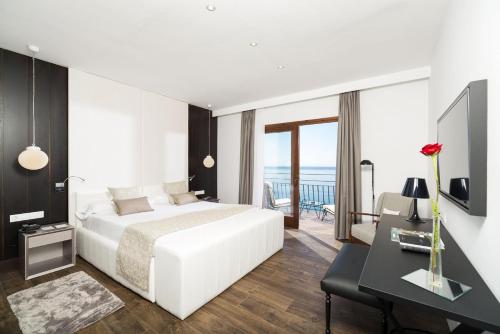 a bedroom with a white bed and a balcony at Hotel Santa Marta in Lloret de Mar