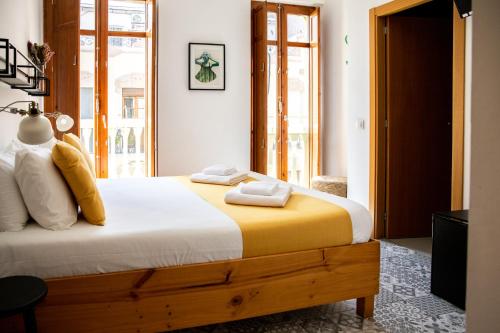 ein Schlafzimmer mit einem großen Bett mit gelben und weißen Kissen in der Unterkunft Zalamera BnB in Valencia