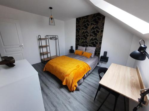 um quarto com uma cama com um cobertor amarelo em gîte Mouettes et Chouettes em Saint-Hilaire-Petitville