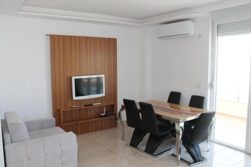 a dining room with a table and chairs and a television at Blue Apartments & Hotel Shengjin in Shëngjin