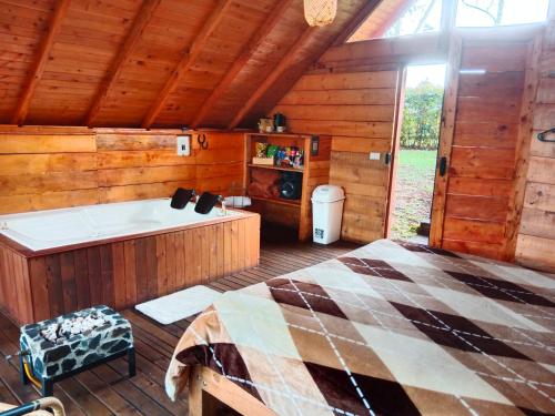a bedroom with a bed and a tub in a cabin at Cabaña Arrayanes in Rionegro