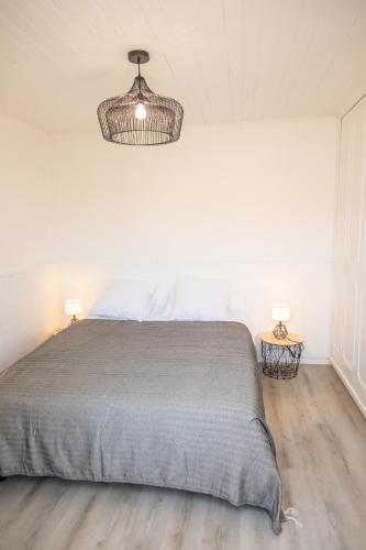 - une chambre blanche avec un lit et un lustre dans l'établissement villa Hortense, à Saint-Martin-de-Ré
