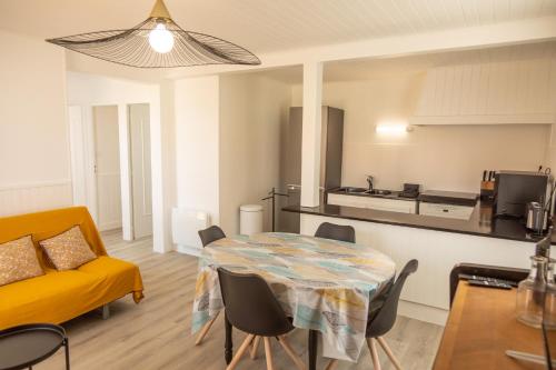 een woonkamer met een tafel en een gele bank bij villa Hortense in Saint-Martin-de-Ré