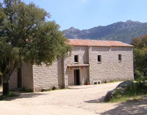 un bâtiment en pierre avec un arbre en face dans l'établissement Home sweet home, à Calangianus