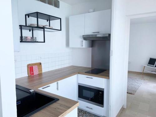 cocina con armarios blancos y encimera de madera en Appartement en bord de mer en Pietranera