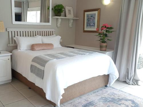 1 dormitorio con 1 cama blanca grande y ventana en Villa Roc Guesthouse - Solar Power en Ballito