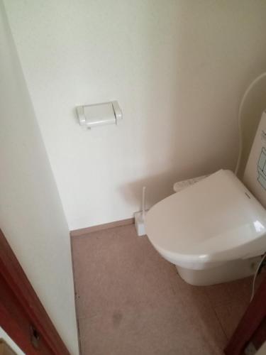 a white toilet in a bathroom with a toilet paper dispenser at Sapporo Guest House Nariya in Sapporo