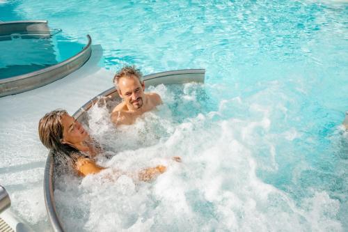 2 personas en una bañera de hidromasaje en una piscina en Le Bristol Leukerbad, en Leukerbad