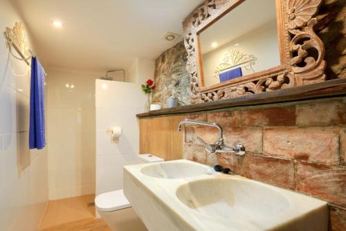 a bathroom with a sink and a mirror and a toilet at El Xalet, El Reixac Casa Rural in Sant Joan de les Abadesses