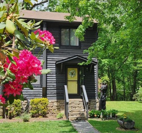 a black house with a yellow door and pink flowers at J.Creek Retreat, creekside townhouse +1 car garage in Maggie Valley