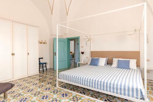 una camera bianca con un letto e una porta blu di Antica Villa del Conte a Porto Cesareo