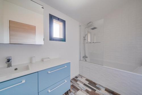 La salle de bains blanche est pourvue d'un lavabo, d'une baignoire et d'un miroir. dans l'établissement La Villa Kudeta - Belle maison avec piscine, à Bouliac