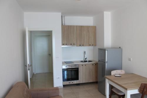 a kitchen with a table and a refrigerator and a table and a dining room at Blue Apartments & Hotel Shengjin in Shëngjin