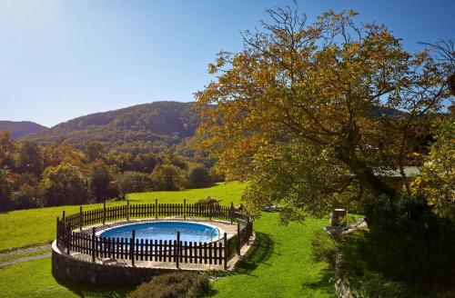 een zwembad in een veld met een hek eromheen bij Galliner, El Reixac Casa Rural in Sant Joan de les Abadesses