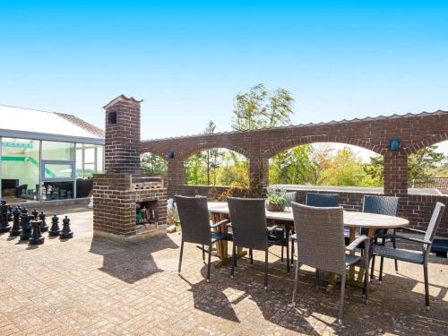 a patio with a table and chairs and a fireplace at 8 person holiday home in Knebel in Knebel