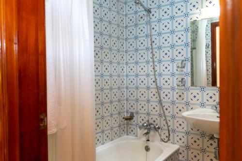 La salle de bains est pourvue de carrelage bleu, d'un lavabo et d'une baignoire. dans l'établissement Flag Hotel Madeira - Ribeira Brava, à Ribeira Brava