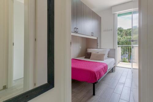 um quarto com uma cama com um cobertor rosa em Lido degli Estensi Seaview Apartment em Lido degli Estensi