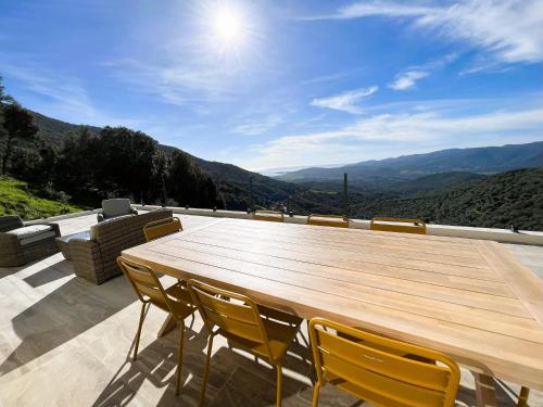 un tavolo in legno e sedie su un patio con vista di Villa à louer Corse du Sud Sollacaro 8pers a Sollacaro