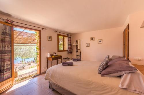 a bedroom with a large bed and a large window at Le Mas de Riri in Celles