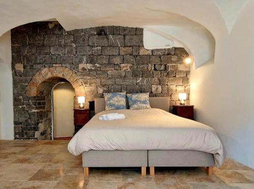 a bedroom with a large bed with a stone wall at La Tour de Pezene in Anduze
