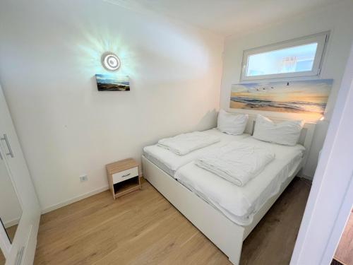 1 dormitorio con 1 cama con reloj en la pared en Ferienpark Sierksdorf App 793 - Lillis Oase, en Sierksdorf