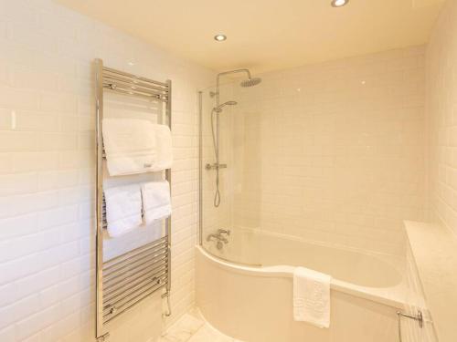 a bathroom with a tub and a shower with towels at The Old Barn - cottage with spectacular lake view in Port of Menteith