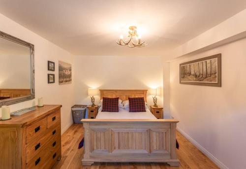 um quarto com uma cama, uma cómoda e um espelho em The Old Barn - cottage with spectacular lake view em Port of Menteith