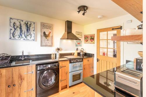 a kitchen with a stove and a washer and dryer at The Old Barn - cottage with spectacular lake view in Port of Menteith