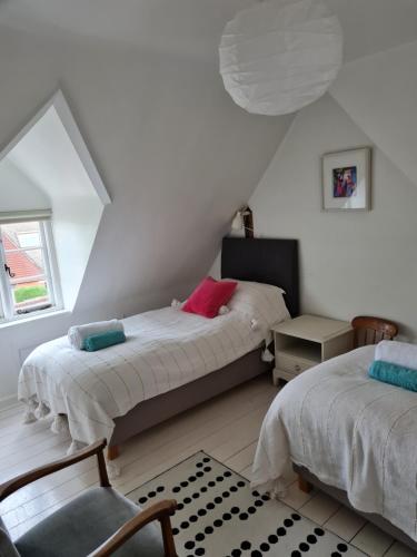a attic bedroom with two beds and a chair at Beggar's Lane Cottage in Winchester