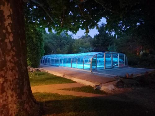 a long glass building with a blue ceiling at Maison charmante au Thor + Piscine in Le Thor