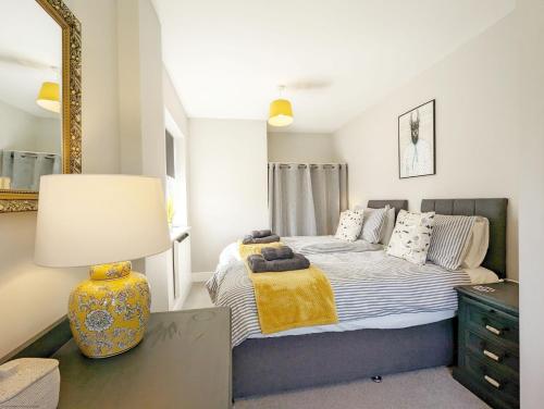 a bedroom with a bed with a lamp and a mirror at Pebblestone in East Wittering