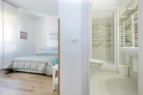 a white bedroom with a bed and a bathroom at B&B Felicioni in Fiumicino