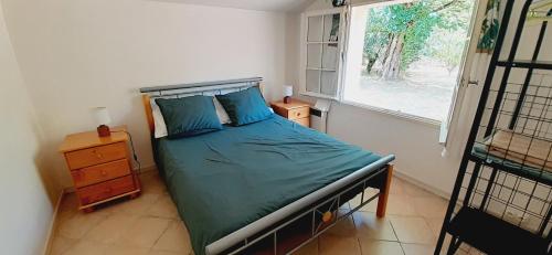 een slaapkamer met een bed met groene lakens en een raam bij La petite maison du Bosc in Saint-Antonin