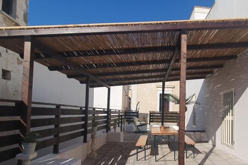 eine hölzerne Pergola mit einem Tisch und Stühlen auf einer Terrasse in der Unterkunft La Stella Marina in Matino