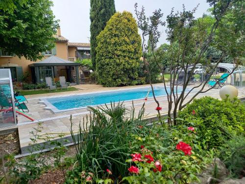 a swimming pool in a yard with flowers at Maison charmante au Thor + Piscine in Le Thor