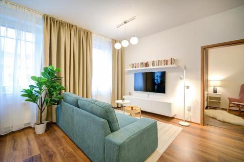 een woonkamer met een blauwe bank en een tv bij Urban Apartments in Brno