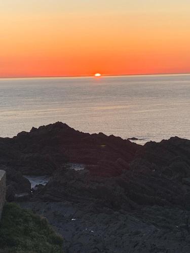a sunset over the ocean with the sun setting on the horizon at Home from Home B&B in Hartland