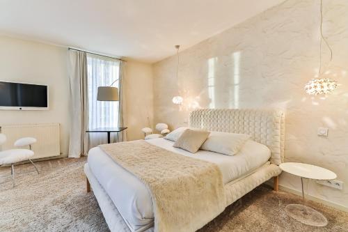 a white bedroom with a bed and a tv at Maison Marie Barrault in Les Herbiers