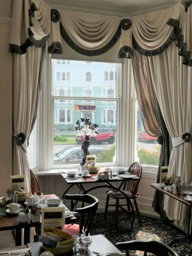 a dining room with a table and a large window at The Cumberland in Llandudno