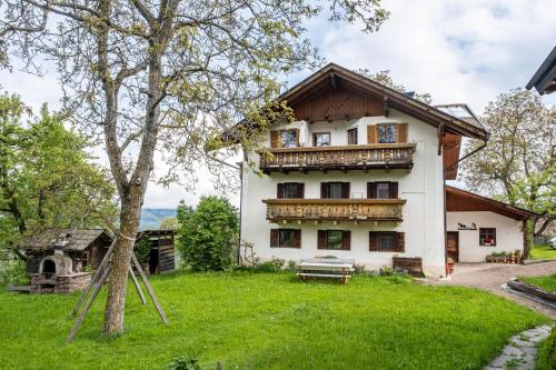 a house with a balcony and a tree at Stablerhof Apt Löwenzahn in Cornedo all'Isarco
