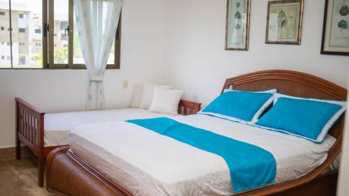 a bedroom with two beds with blue pillows and a window at Monserrat Residences in Las Terrenas