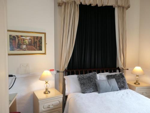 a bedroom with a bed with two lamps and a window at The Cumberland in Llandudno