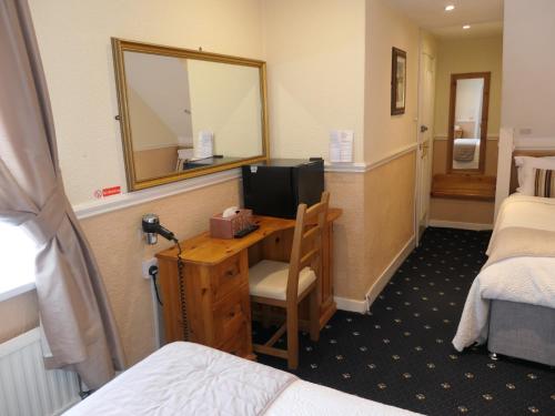 a room with a desk with a television and a mirror at The Cumberland in Llandudno